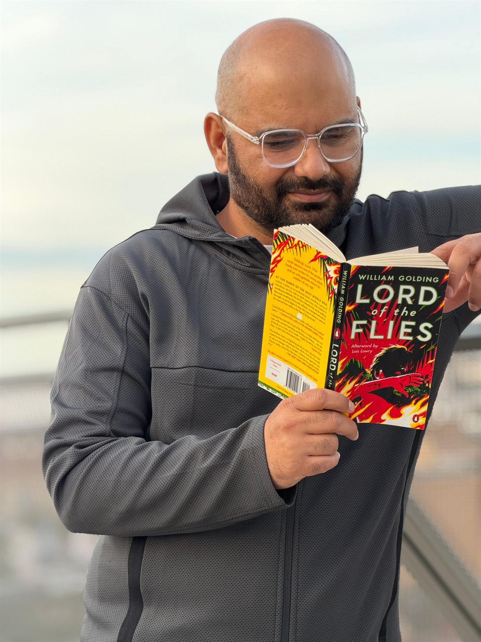 Khurram reading a copy of Lord of the Flies outdoors