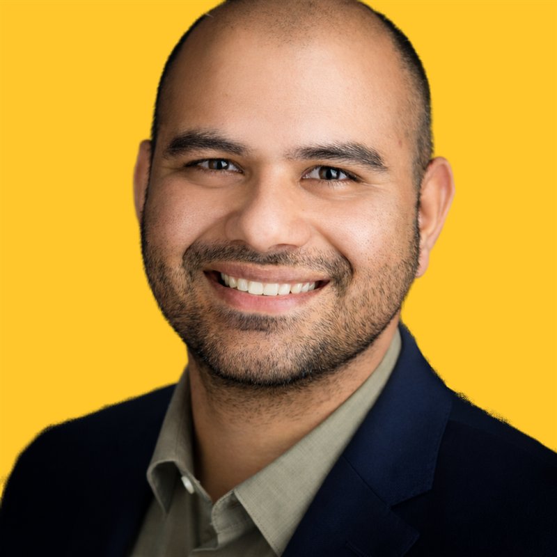 Portrait of Khurram Iftikhar, smiling, on a yellow background